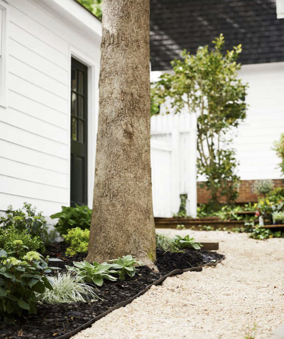 This Yardzen yard is covered in shade and partial shade. The addition of mulch and gravel throughout the yard makes this space quite low-water. Photo via Country Living