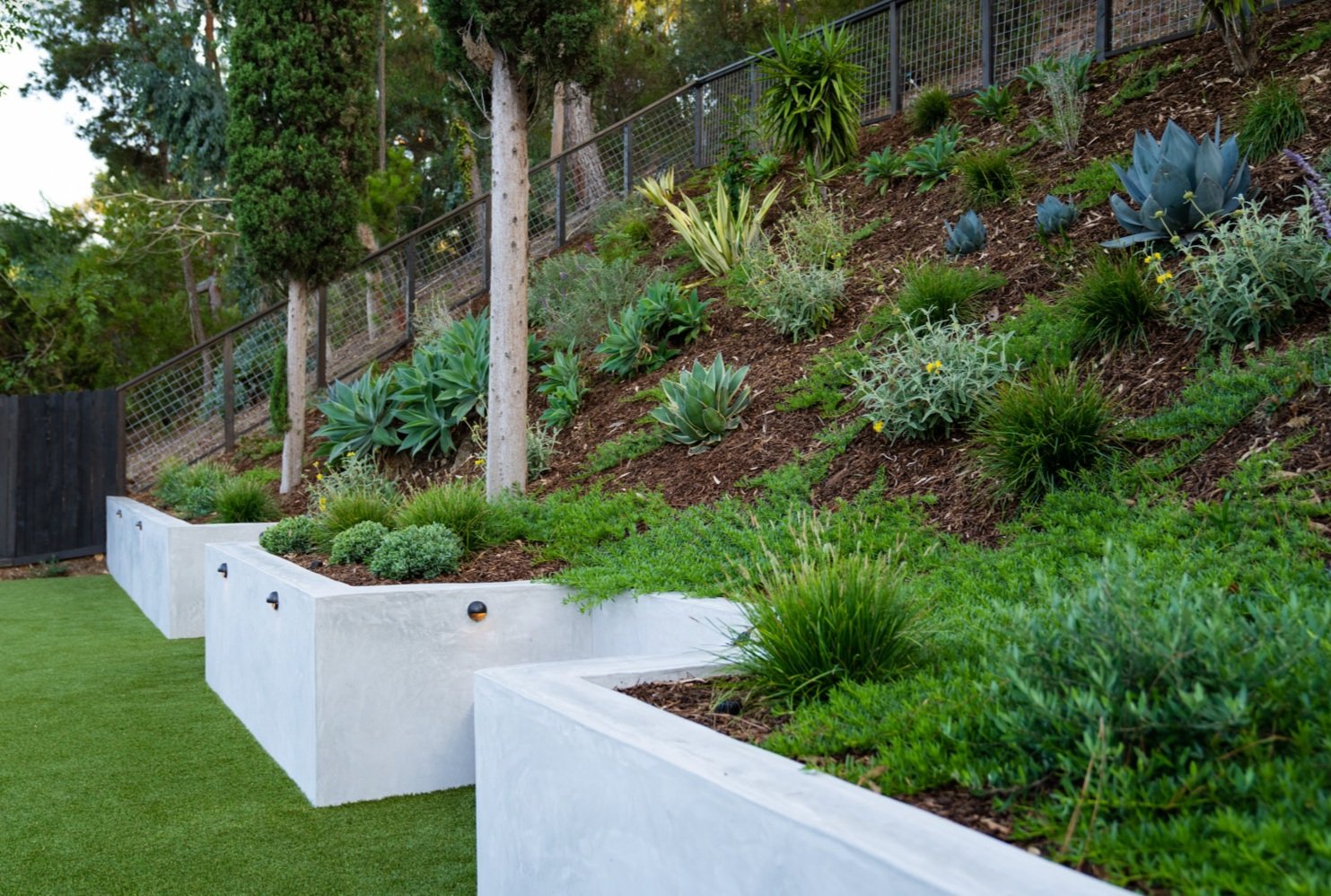 A sloped Yardzen yard transformed by artificial turf and smart landscape design decisions