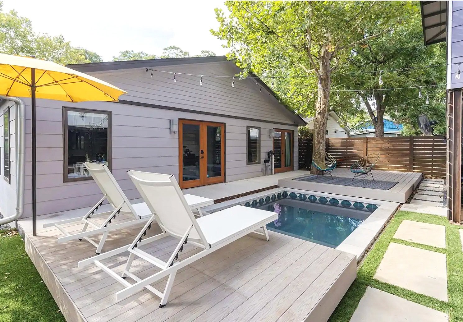 Narrow backyard with tiled plunge pool and decking with seating on either side