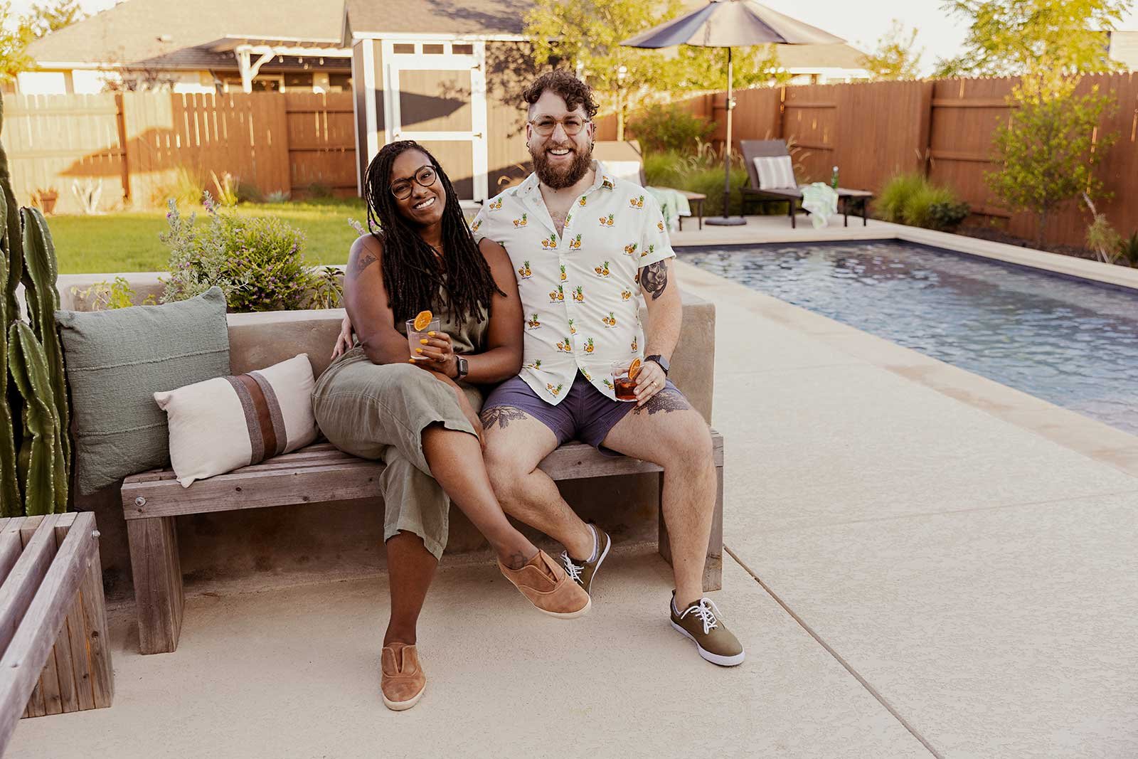 Stacey and Sean Matthew enjoying their new backyard landscape, where a new concrete planter doubles as a seatback for a rustic modern bench.