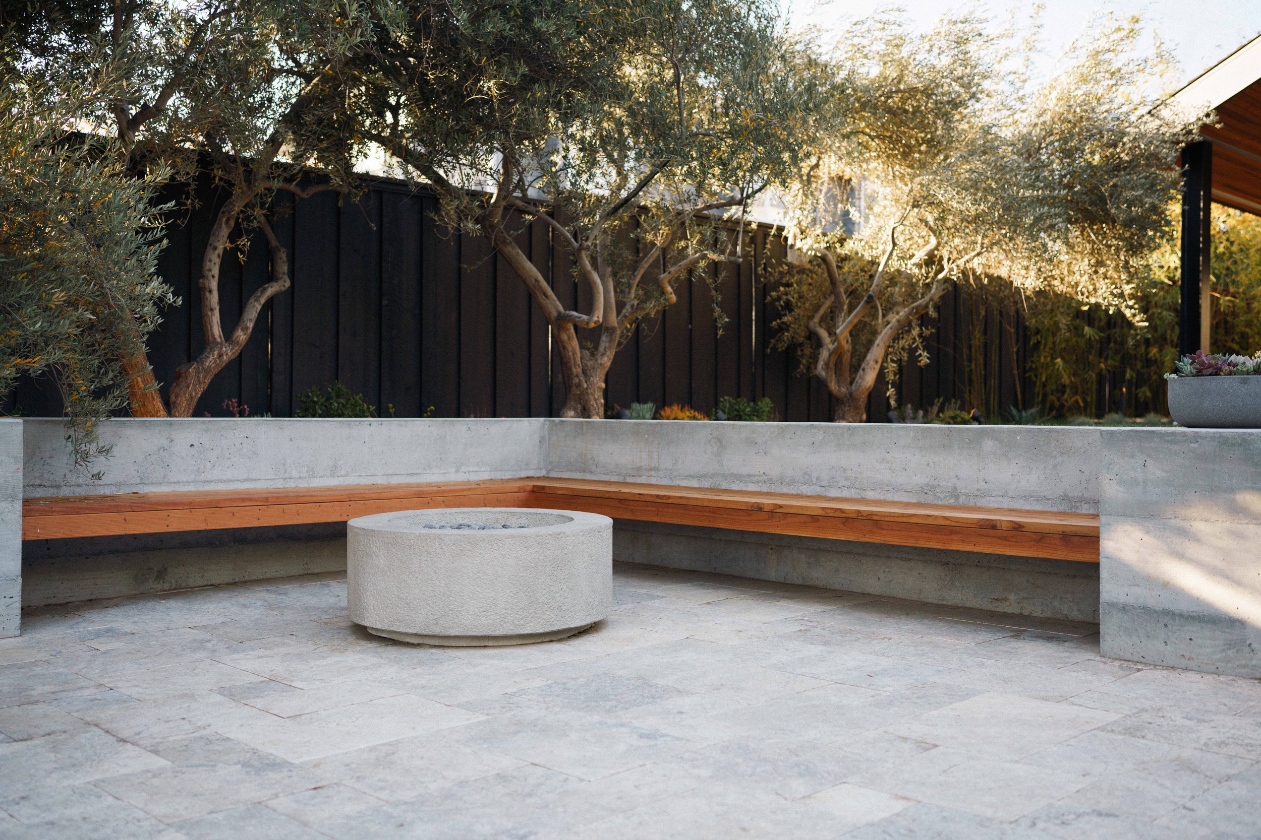 Modern round fire pit with concrete and wood built-in seating