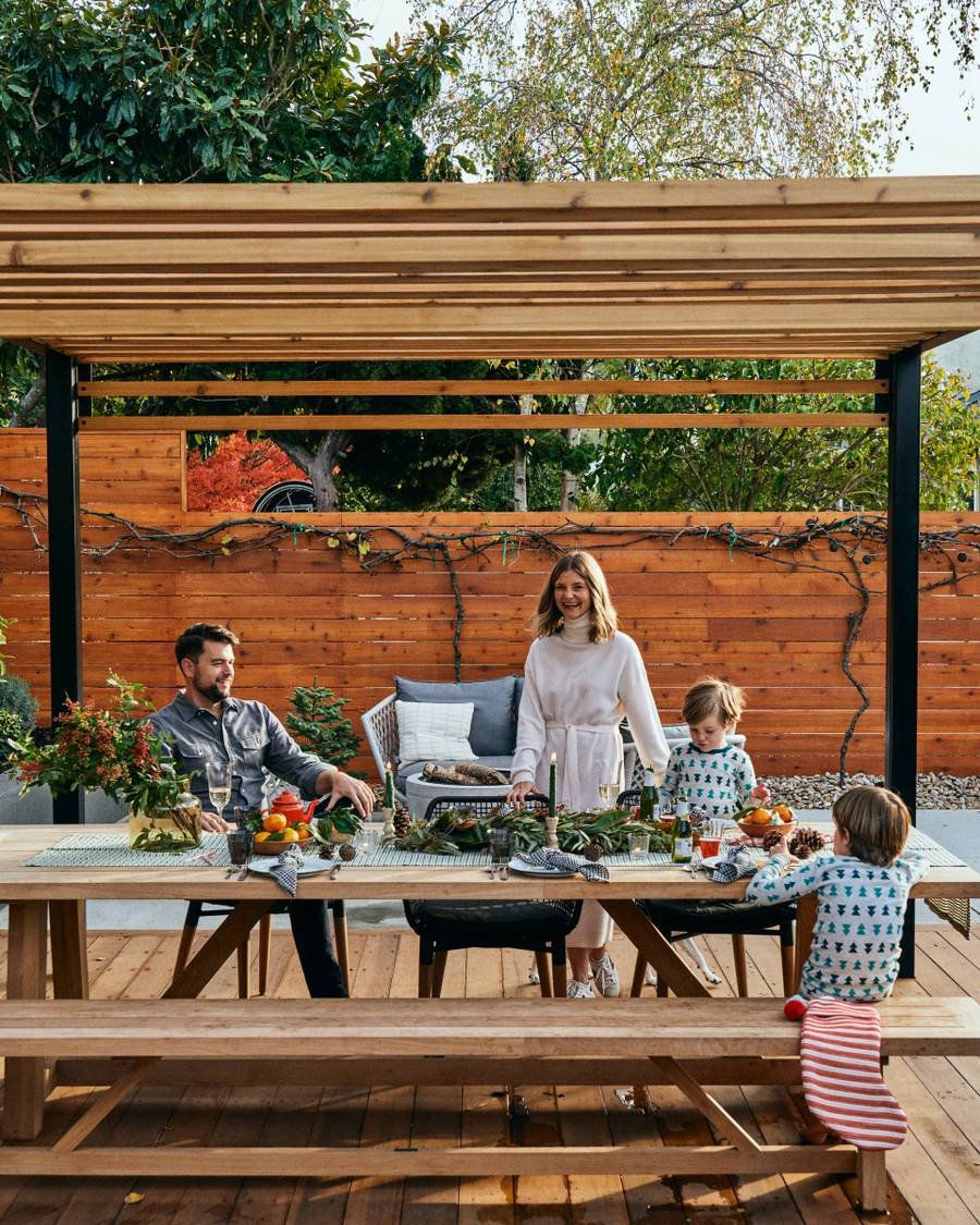 black metal frame pergola with custom wood slat roof over a dining area with a happy family